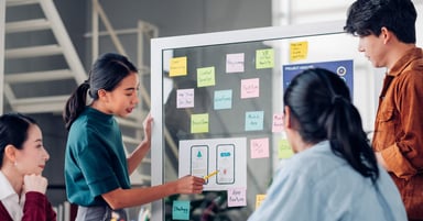 office workers looking at stickies on a board 