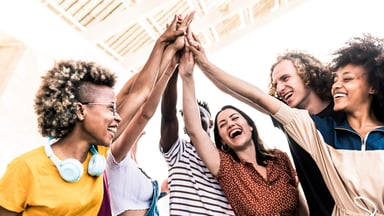 Enthusiastic group of people holding up one hand together in the air