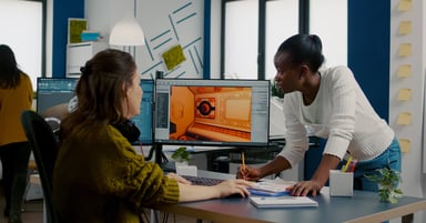 Two women at a desk with a computer screen open next to them