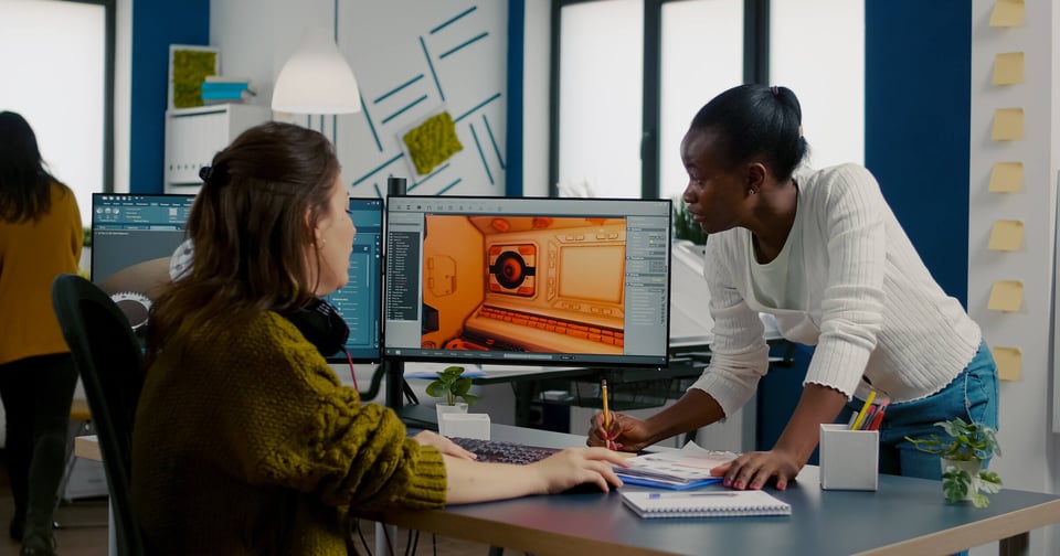 Two women at a desk with a computer screen open next to them