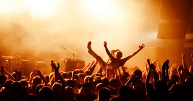 Smoky concert hall with fans dancing and holding up their hands