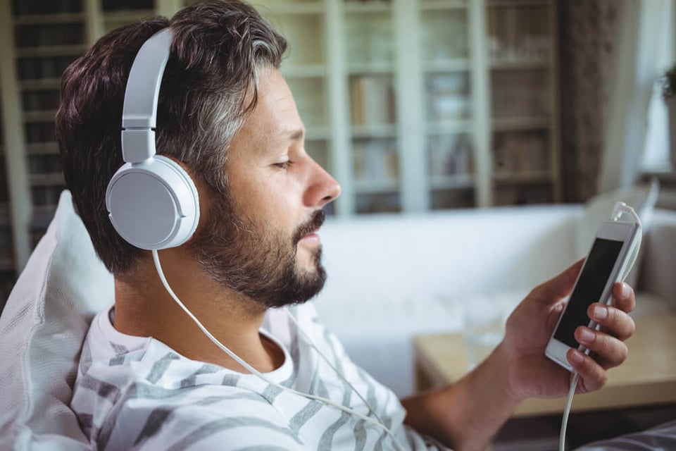 Bearded man wearing over-the-head headset, with phone in hand