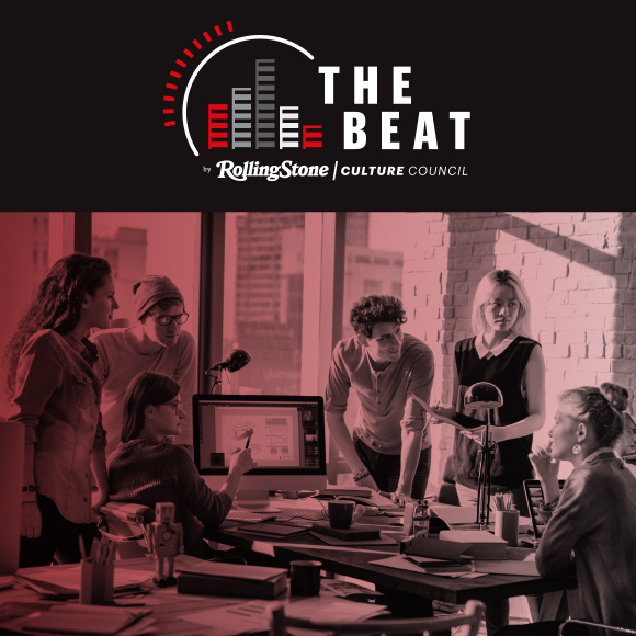 Group of people huddle around a desk in an office setting.
