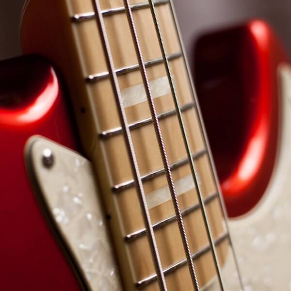 The neck of a red bass guitar.